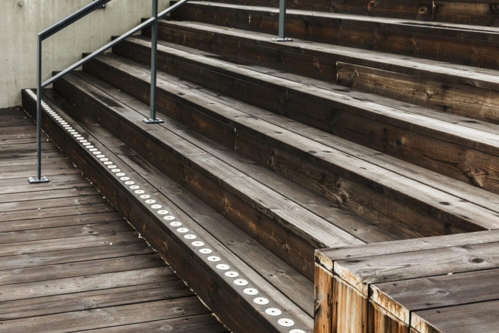 Vita kontrastprickar med skruvhål på trappa i trä utomhus